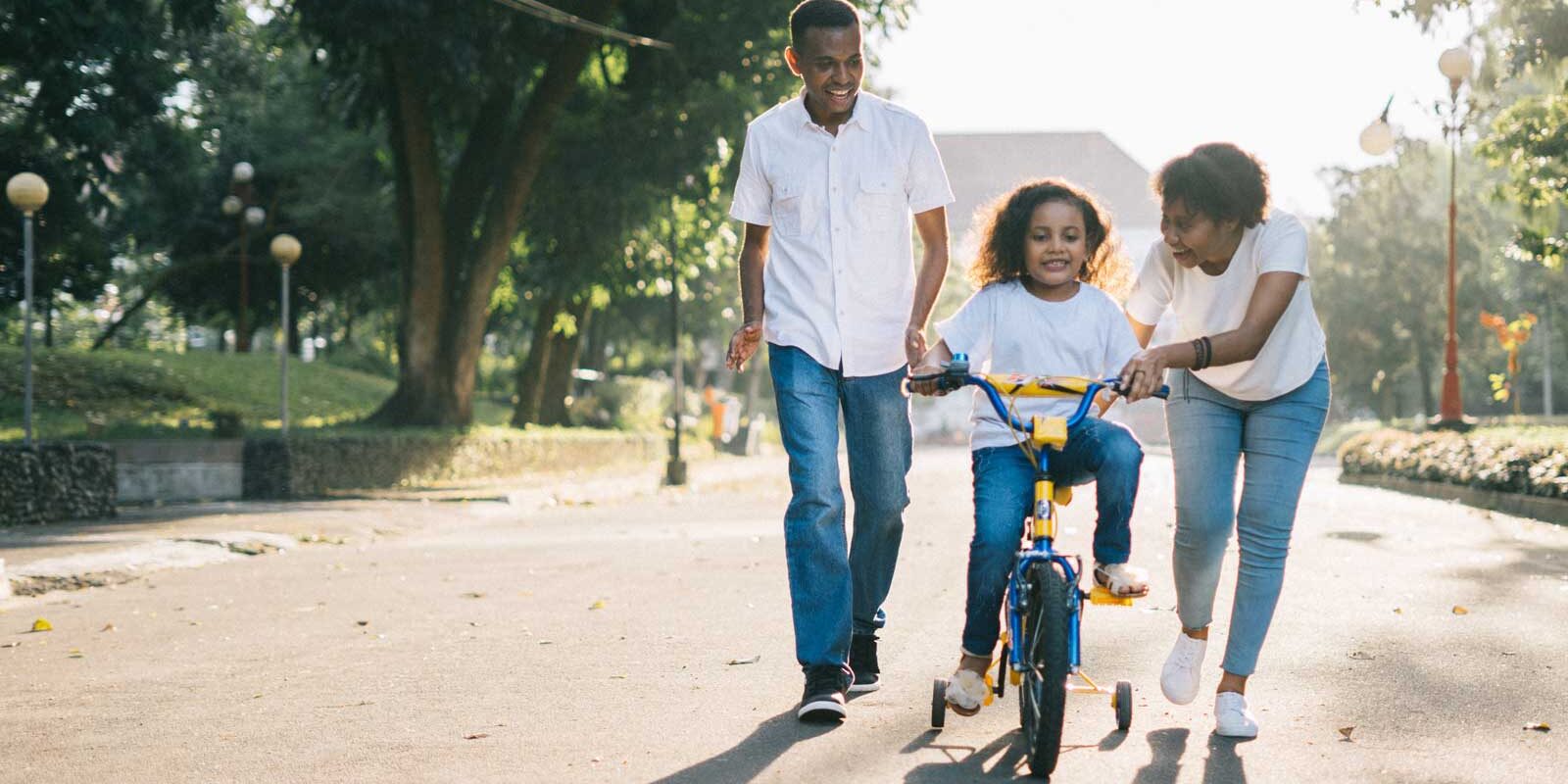 Co-Parenting pair teaching their daughter to ride a bike.