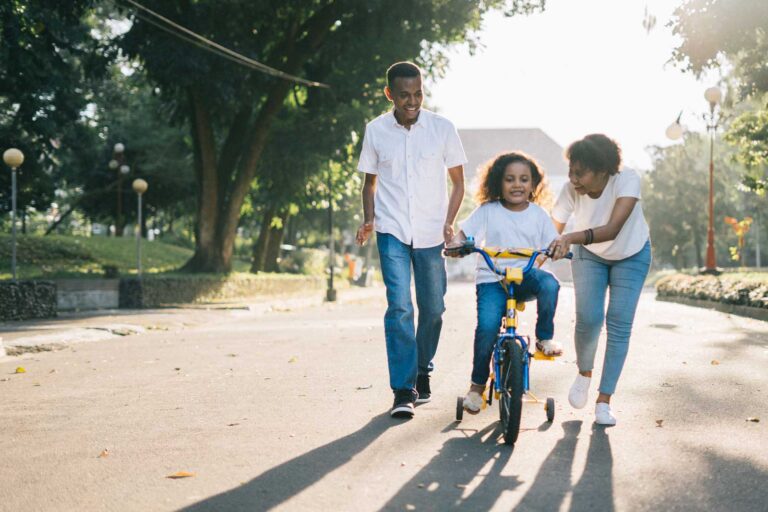 Co-Parenting pair teaching their daughter to ride a bike.